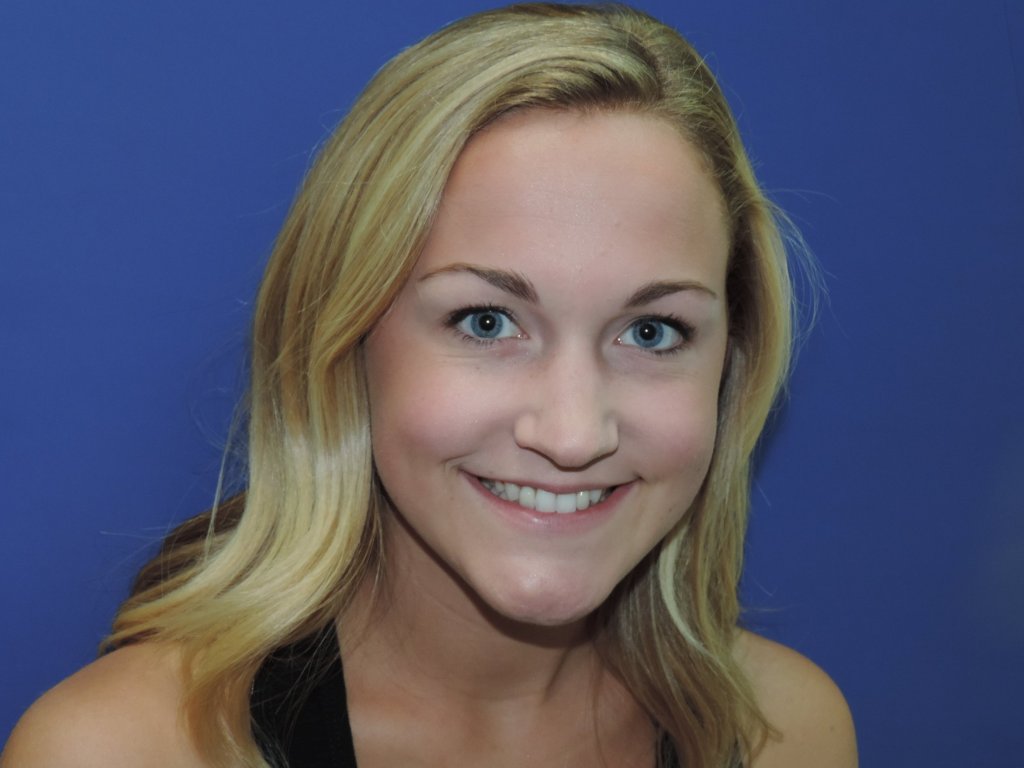 A blonde woman with blue eyes smiling after implant supported restorations